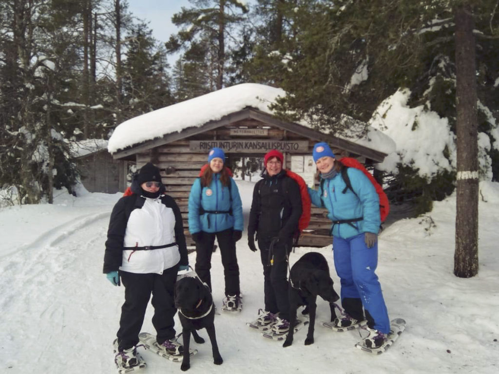 Heidi sekä Otto-koira, Miina, Sirpa Turo-koiran kanssa sekä Seikkailuapinoiden Heidi Riisitunturin kansallispuiston portilla lumikengät jalassa valmiina lähtöön. 