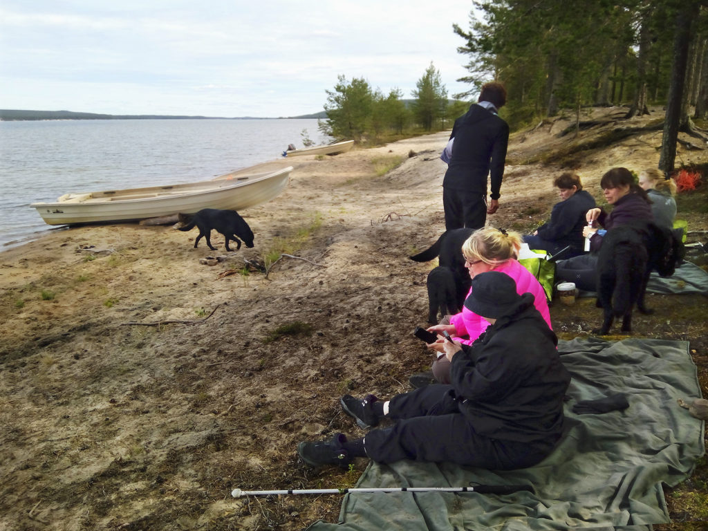 Seikkailijat värjöttelemässä hiekkarannalla vilttien päällä koirien nauttiessa vapaudesta ja vedestä. 